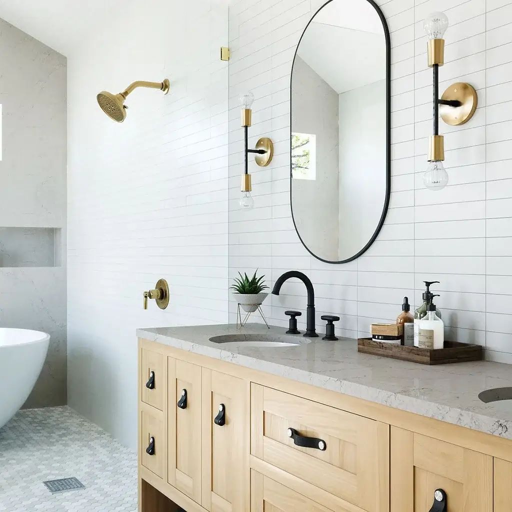 Bathroom with an oak vanity, stone top, brass fixtures and white subway tile